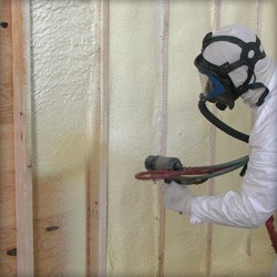 foam tech spraying stud wall cavity with spray foam
